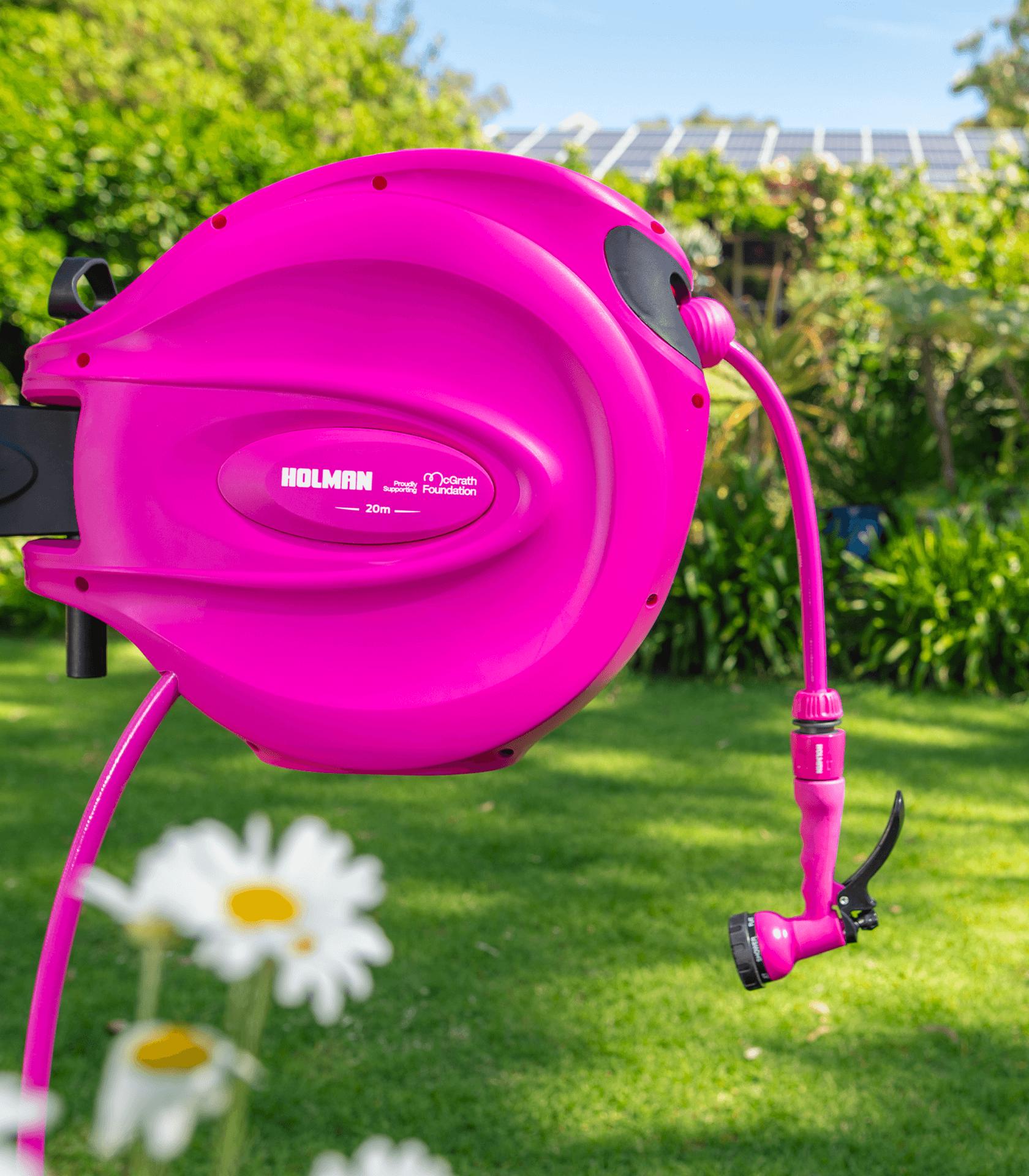 Holman 20m pink retractable garden hose reel supporting the McGrath Foundation, mounted in a sunny garden.